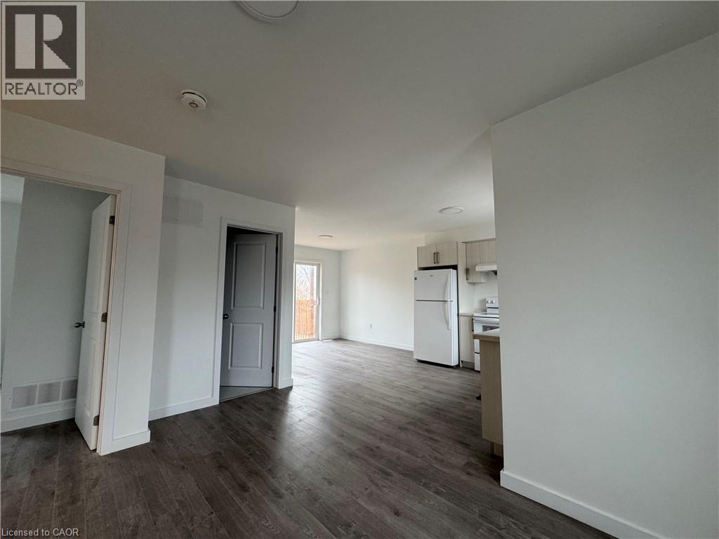 A spacious room with a kitchenette and a door leading to another room.