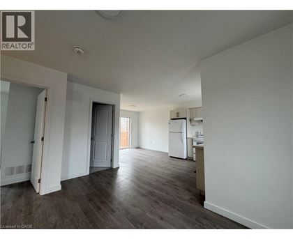 A spacious room with a kitchenette and a door leading to another room.