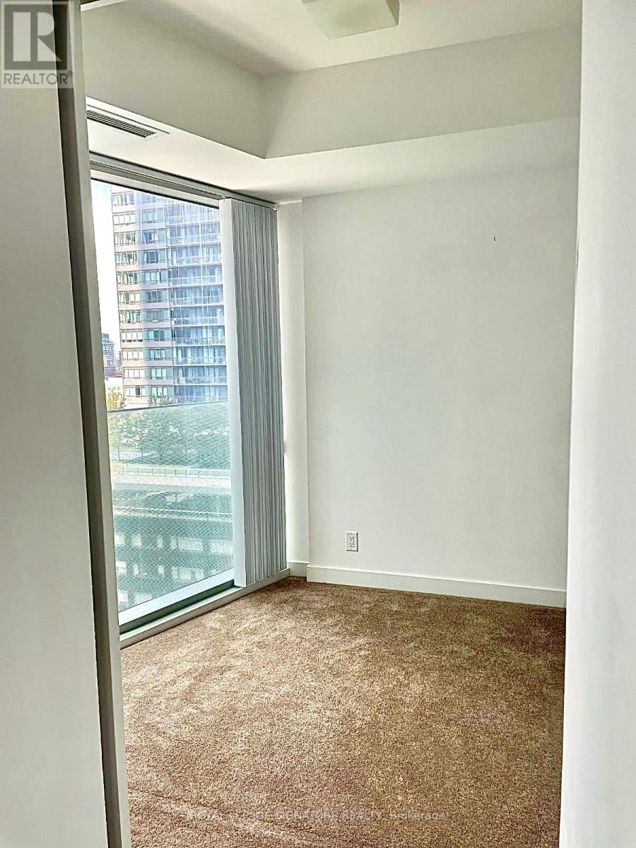 A room with a carpeted floor and a window with a view of a building outside.