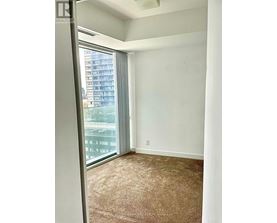 A room with a carpeted floor and a window with a view of a building outside.
