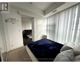 A bedroom with a bed covered in a blue velvet bedspread and a carpeted floor.