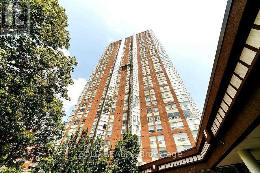 A tall red brick building with many windows is seen from a low angle.