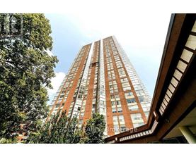 A tall red brick building with many windows is seen from a low angle.