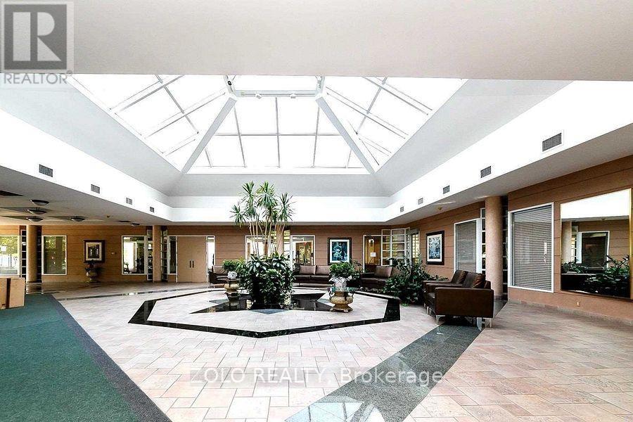 A large open living room with a glass ceiling and a fountain in the middle.