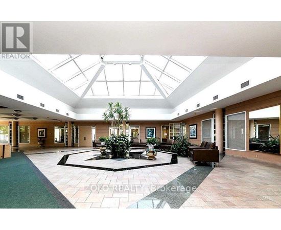 A large open living room with a glass ceiling and a fountain in the middle.
