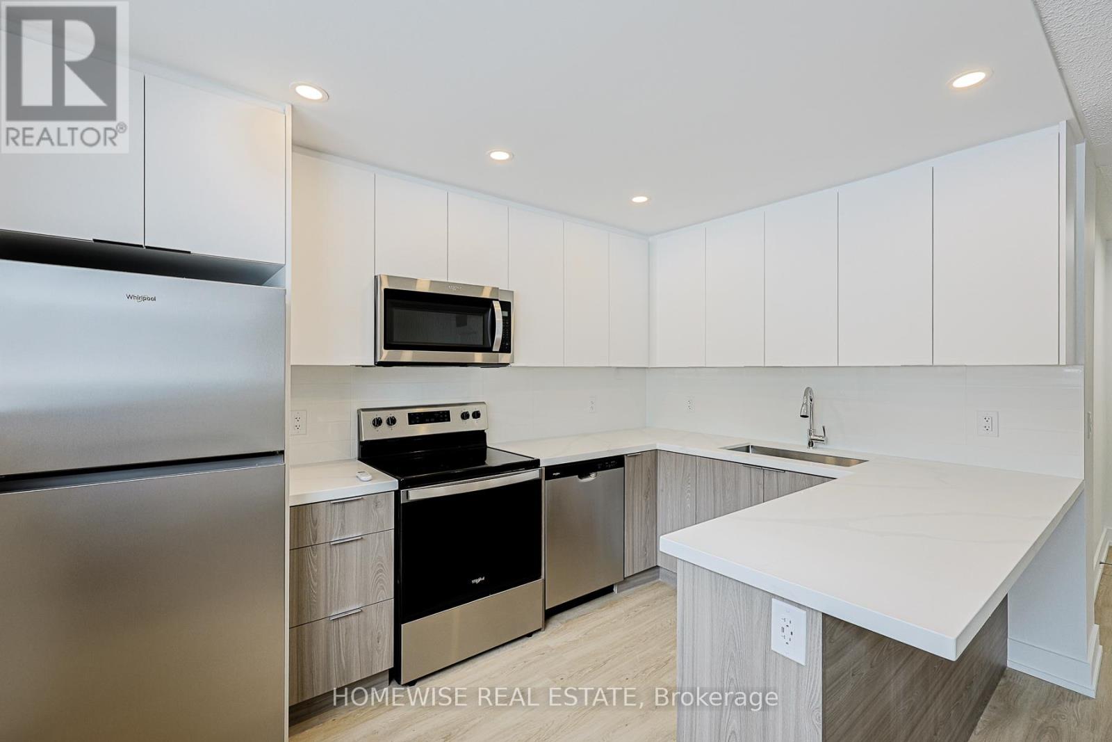 A modern kitchen with white cabinets and stainless steel appliances.