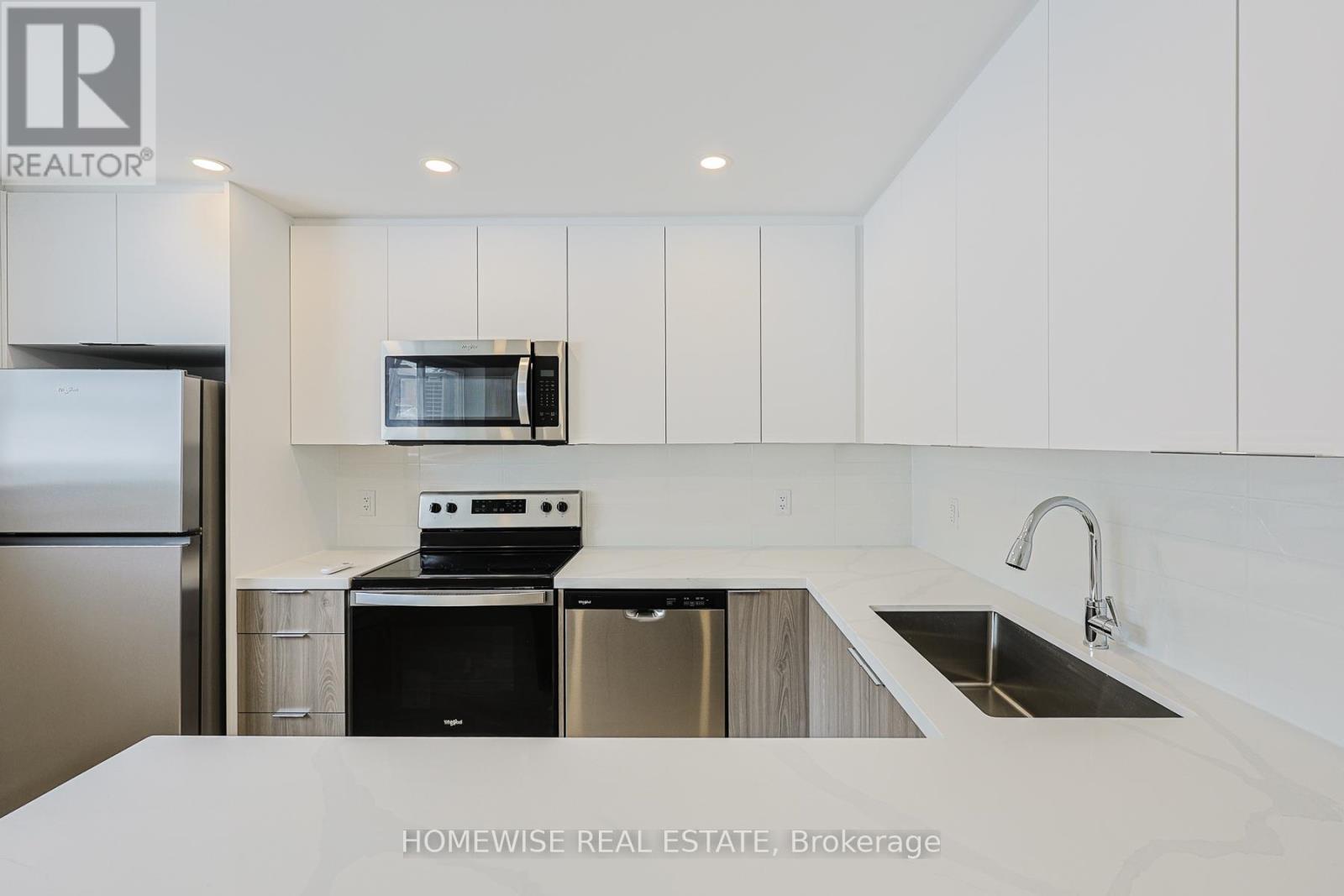A modern kitchen with white cabinets and stainless steel appliances.