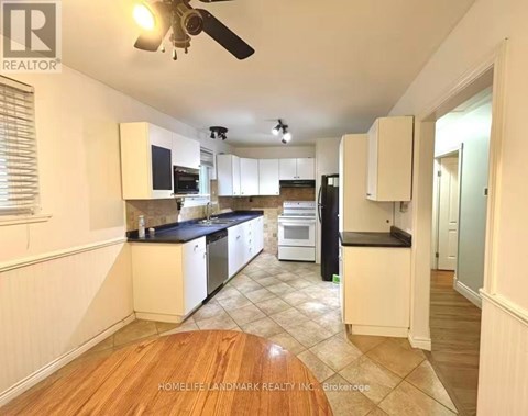 A kitchen with white cabinets and a black countertop.