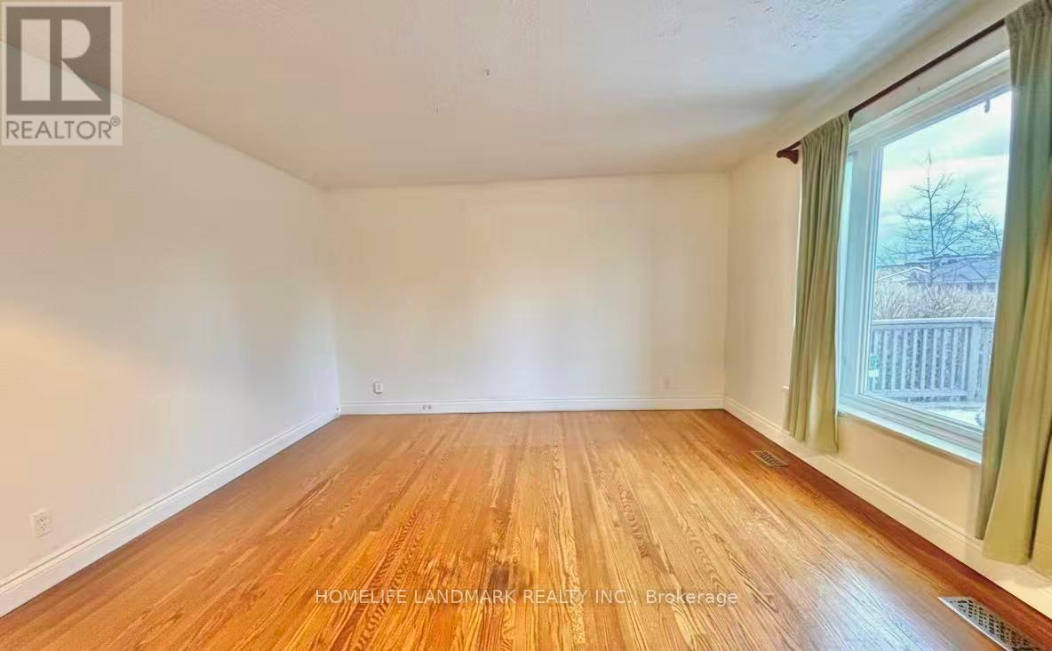 A room with wooden flooring and a window with green curtains.
