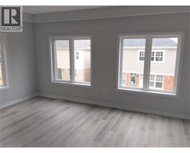 A room with a grey wall and a window with a view of a building.