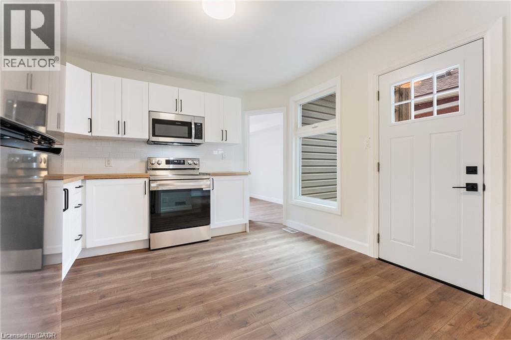 A kitchen with white cabinets and a wooden floor.
