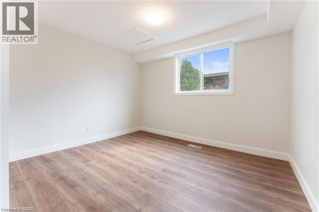 A room with wooden flooring and a window showing trees outside.