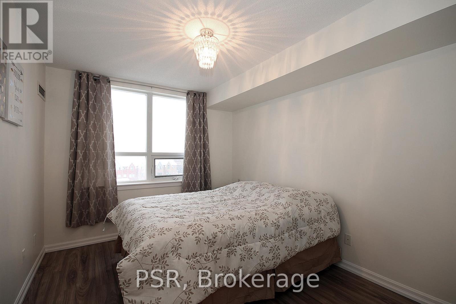 A bedroom with a bed, a window with curtains, and a chandelier.