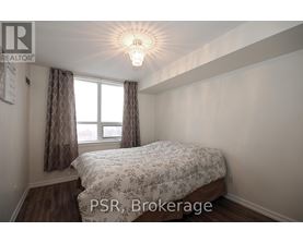 A bedroom with a bed, a window with curtains, and a chandelier.