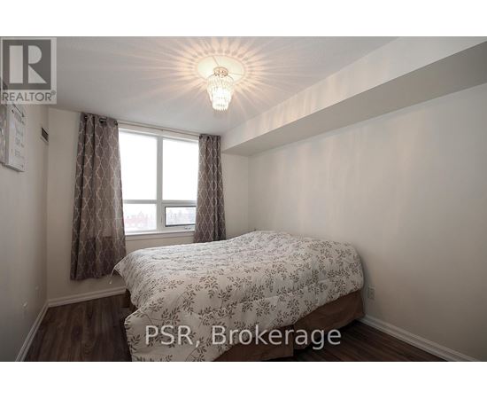 A bedroom with a bed, a window with curtains, and a chandelier.