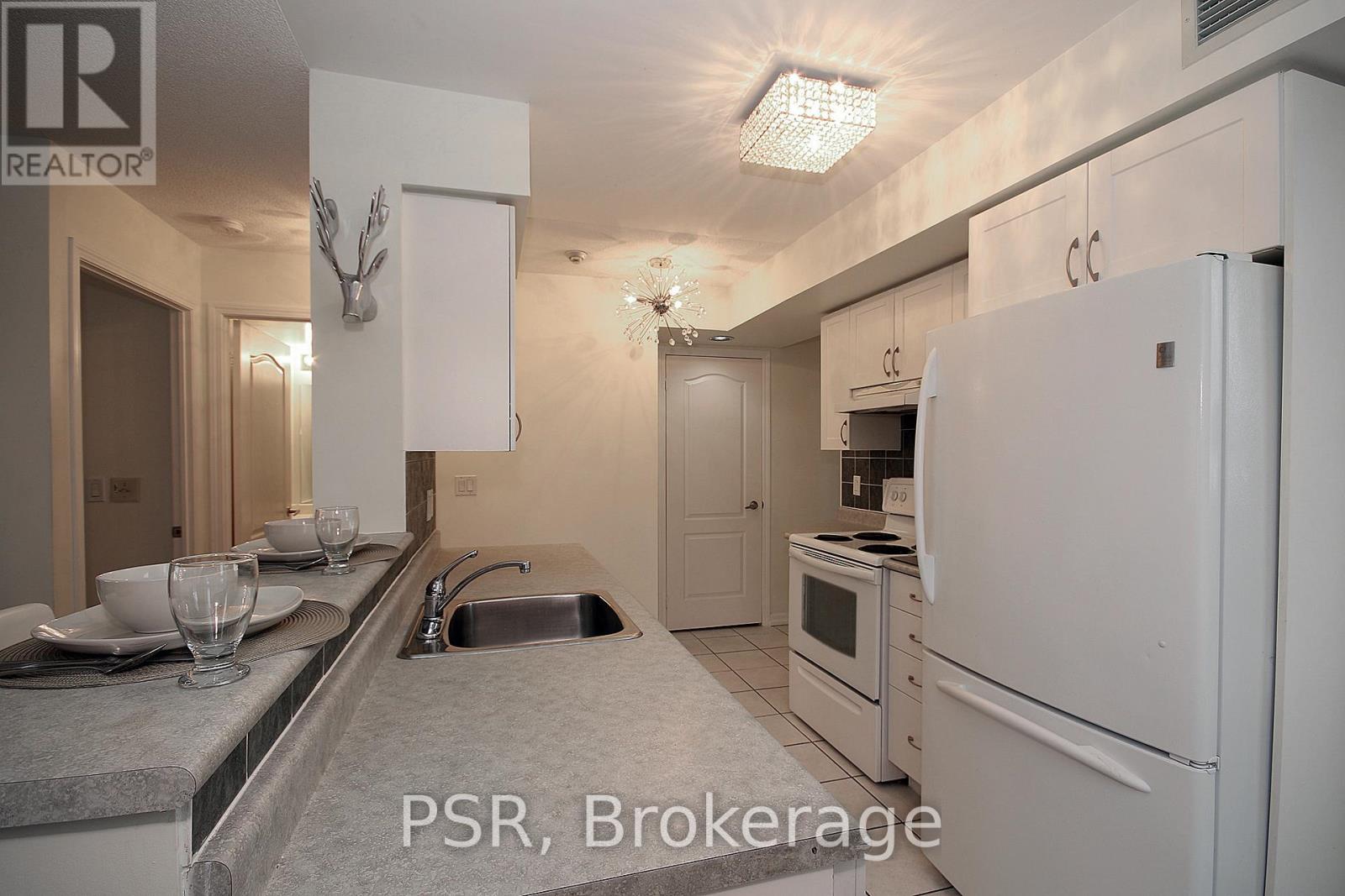 A kitchen with a sink, refrigerator, and microwave.