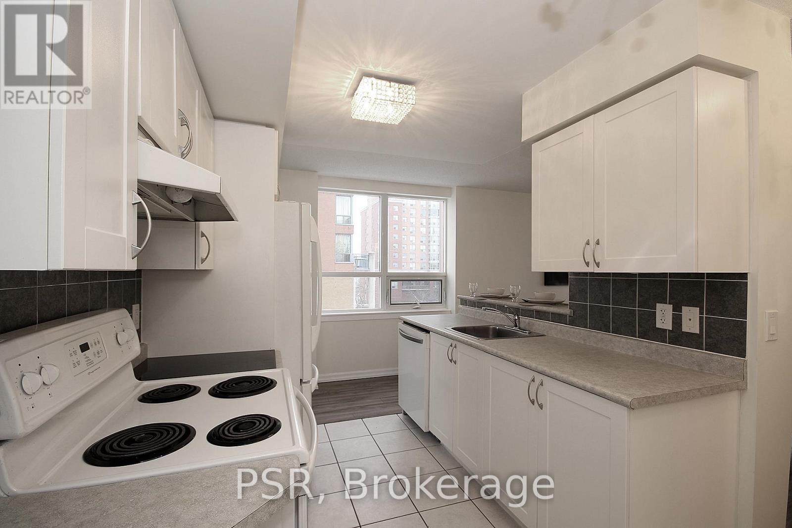 A kitchen with white cabinets and a stove top oven.