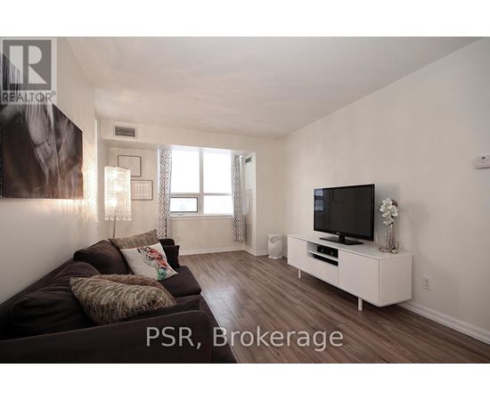 A living room with a brown couch and a television on a white stand.