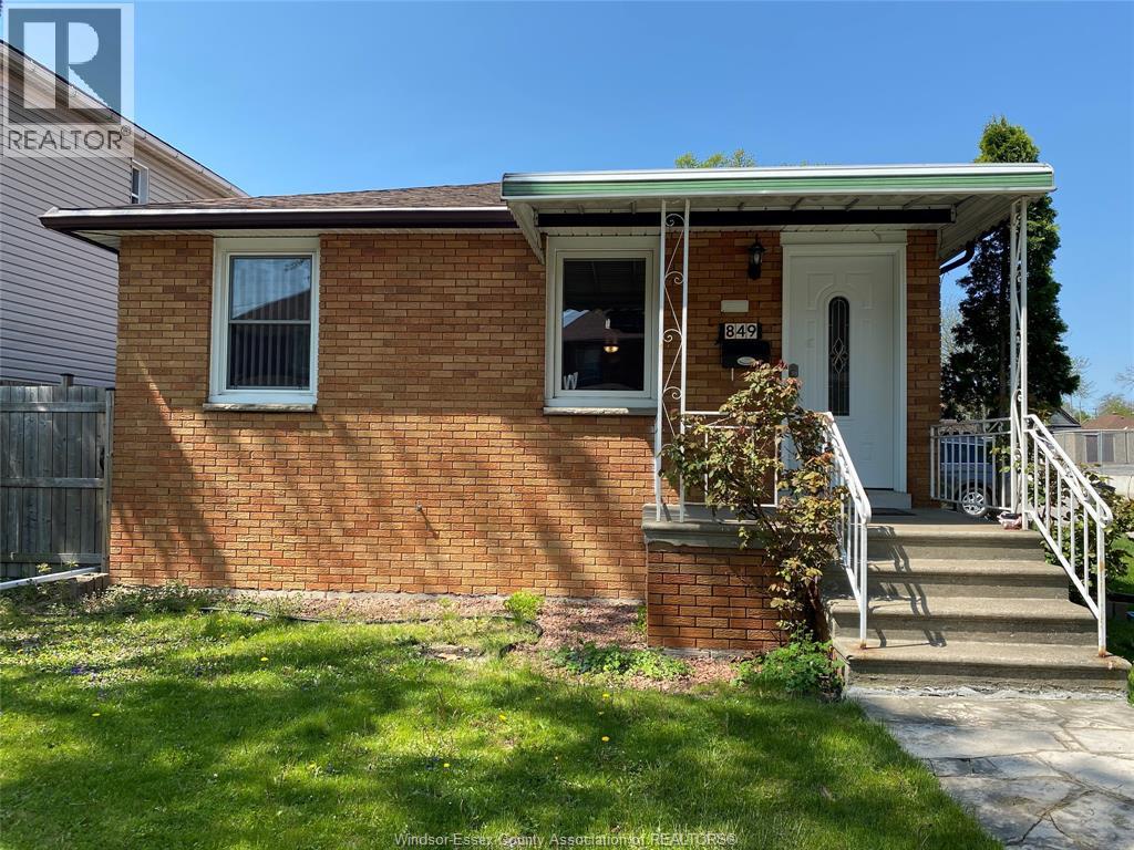 A small red brick house with a white door and windows.