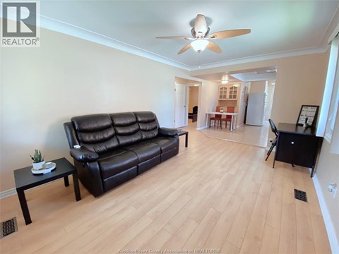 A living room with a black leather couch and a ceiling fan.