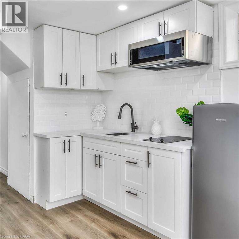 A kitchen with white cabinets and a stainless steel refrigerator.