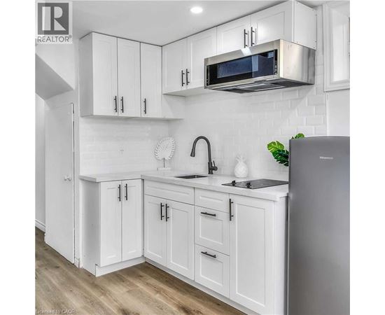 A kitchen with white cabinets and a stainless steel refrigerator.