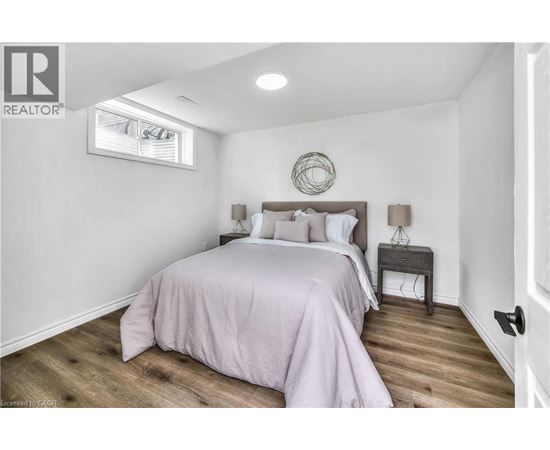 A bedroom with a bed, nightstand, and a window.