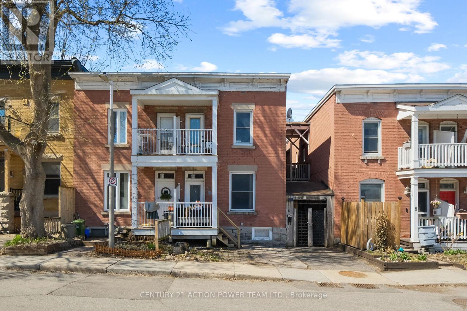 A row of townhouses with a sign that says Century 21 Action Power Team Ltd, Brokerage.