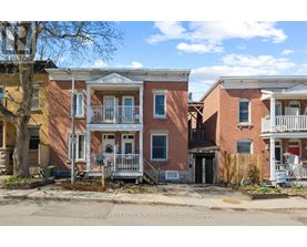 A row of townhouses with a sign that says Century 21 Action Power Team Ltd, Brokerage.