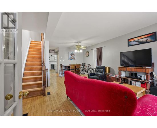 A living room with a red couch and a staircase.