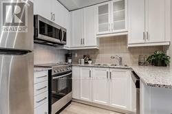 A kitchen with white cabinets and a stainless steel refrigerator.