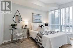 A bedroom with a bed, chair, and a picture on the wall.