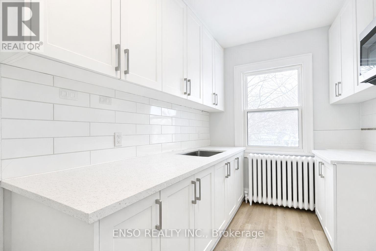 A white kitchen with a window and a radiator.