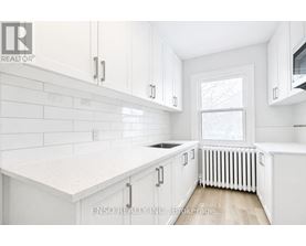 A white kitchen with a window and a radiator.
