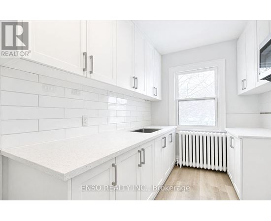 A white kitchen with a window and a radiator.