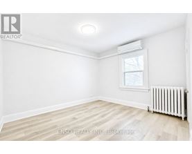 A white room with a window and a radiator on the floor.