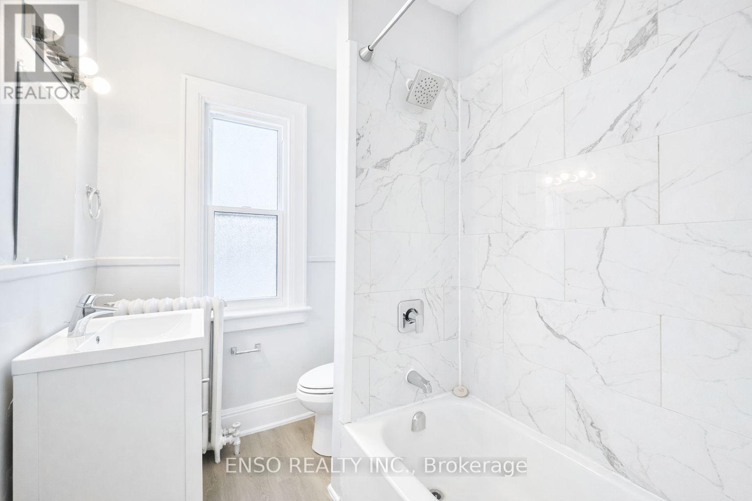 A white bathroom with a marble tile wall.