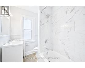 A white bathroom with a marble tile wall.