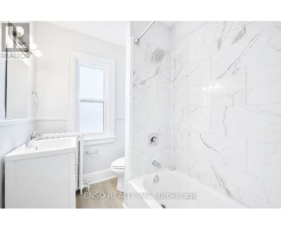 A white bathroom with a marble tile wall.