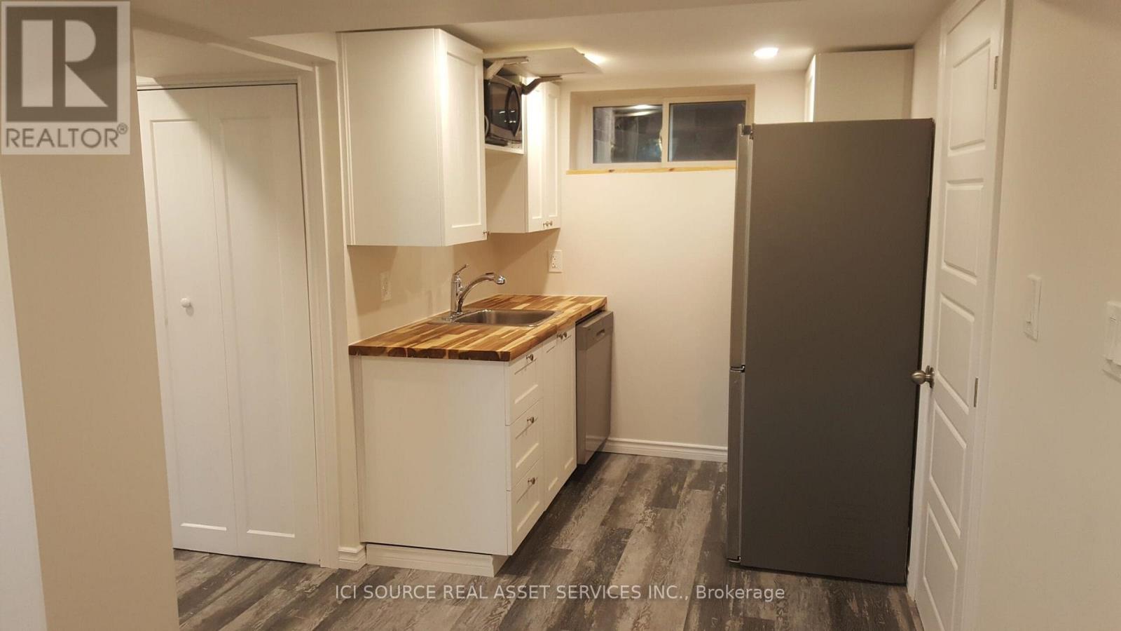 A small kitchen with a wooden countertop and a refrigerator.