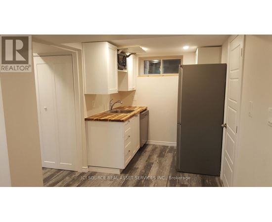 A small kitchen with a wooden countertop and a refrigerator.