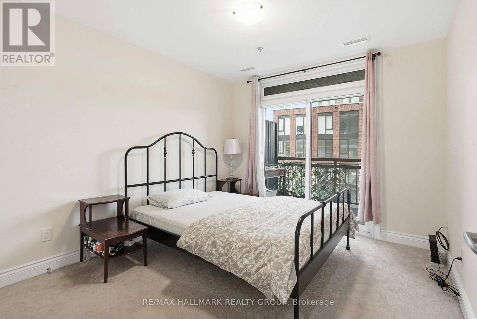 A bedroom with a bed, nightstand, and window.