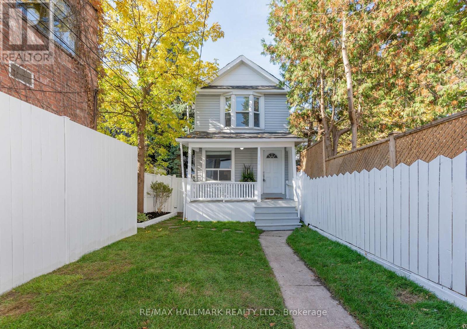 A house with a white picket fence and a tree with yellow leaves.