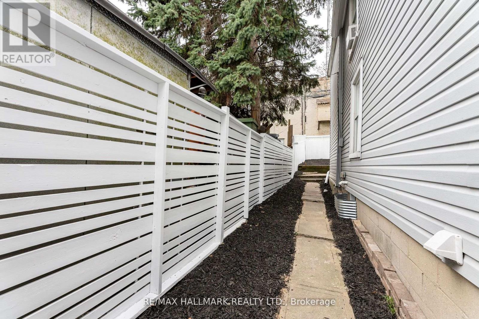 A white fence runs along the side of a building.