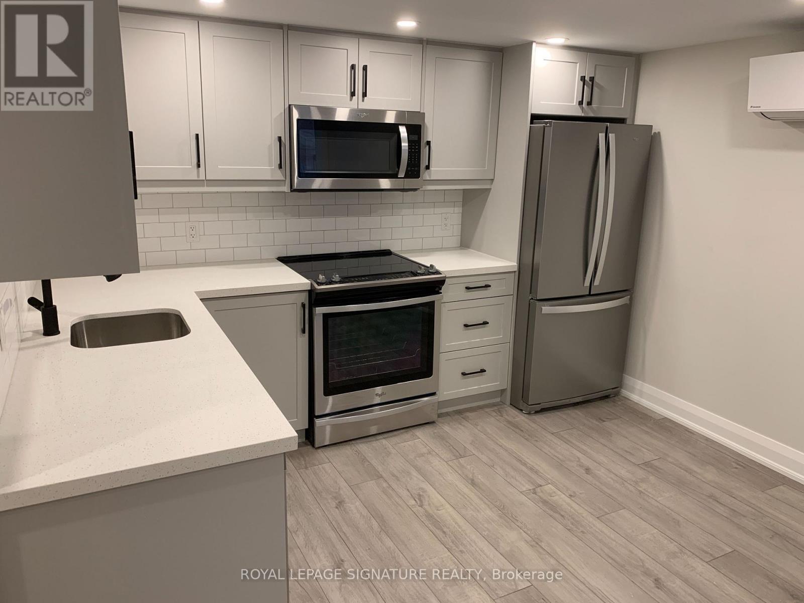 A kitchen with a stove top oven, microwave, refrigerator, and sink.
