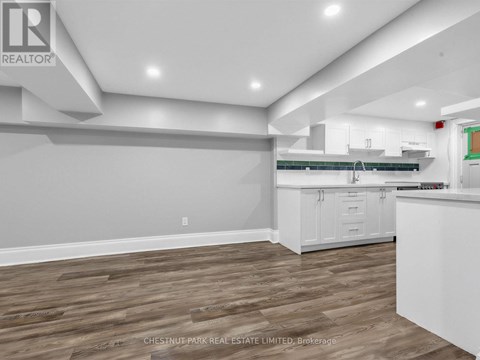 A well-lit kitchen with white cabinets and a wooden floor.