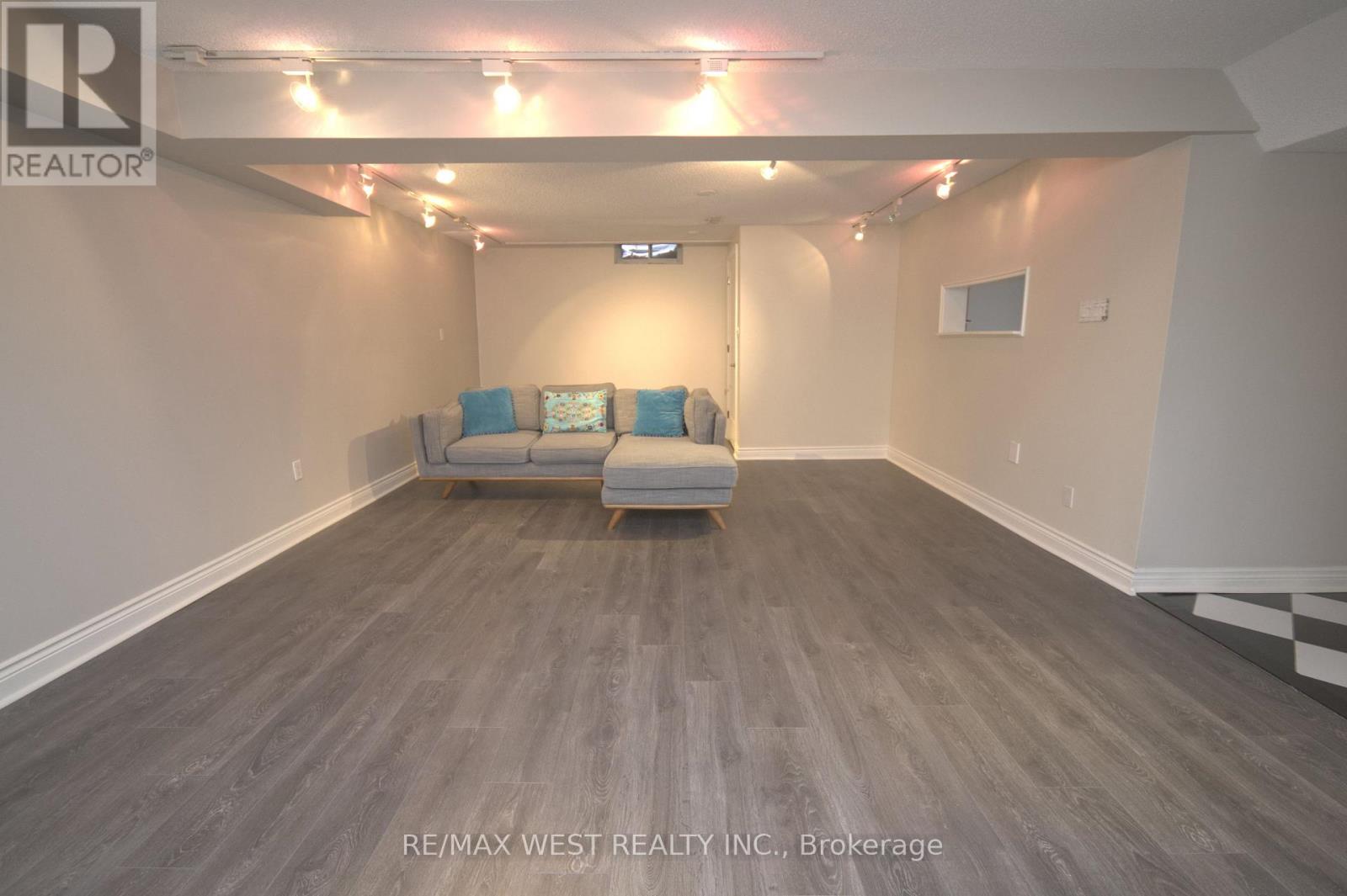 A spacious room with a grey sofa and wooden flooring.
