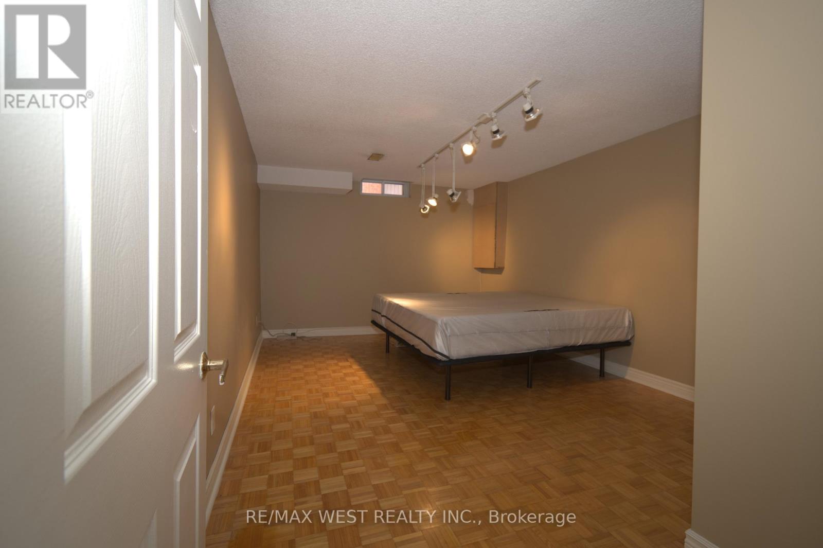 A bedroom with a bed, wooden floor, and a white ceiling.