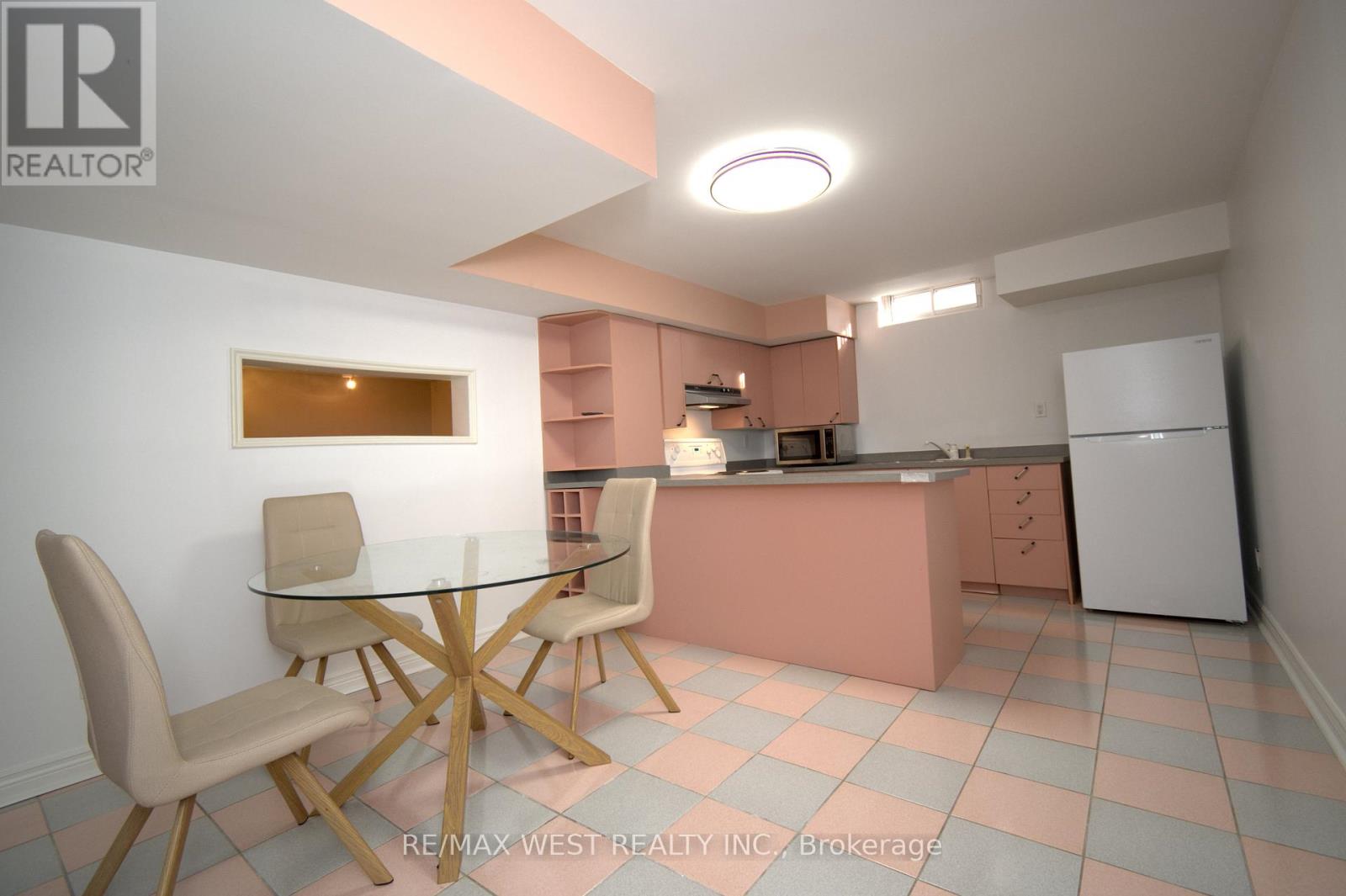 A kitchen with pink cabinets and a glass table with chairs.