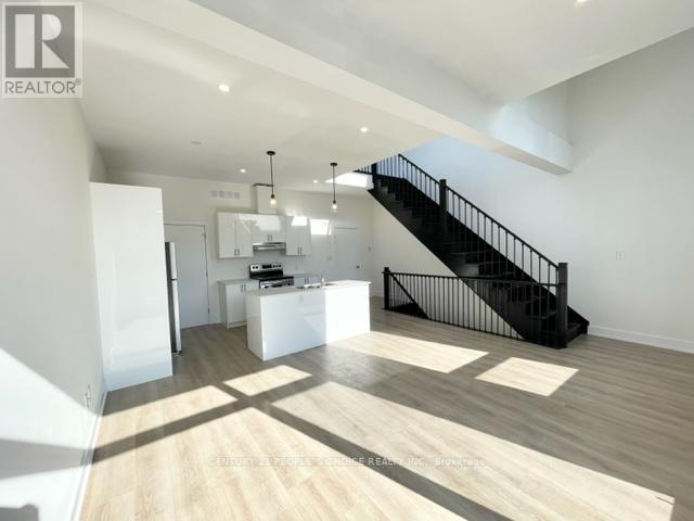 A spacious living room with a black staircase and wooden flooring.